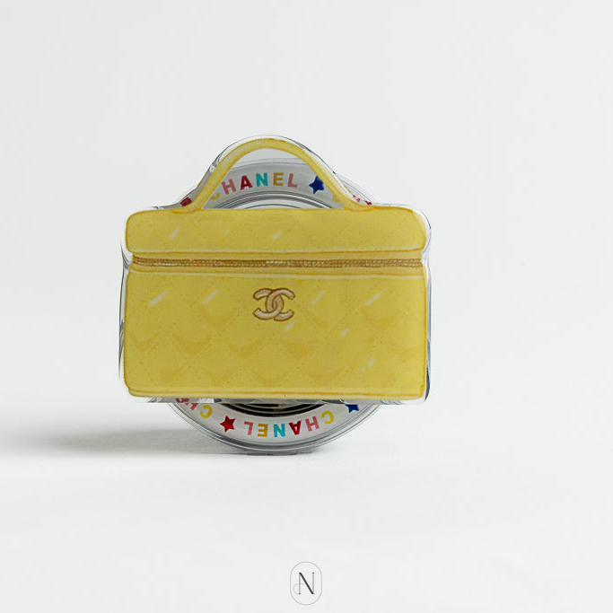 Chanel Vanity Bag Phone Grip. Yellow handbag-shaped pouch with Chanel logo on a white background