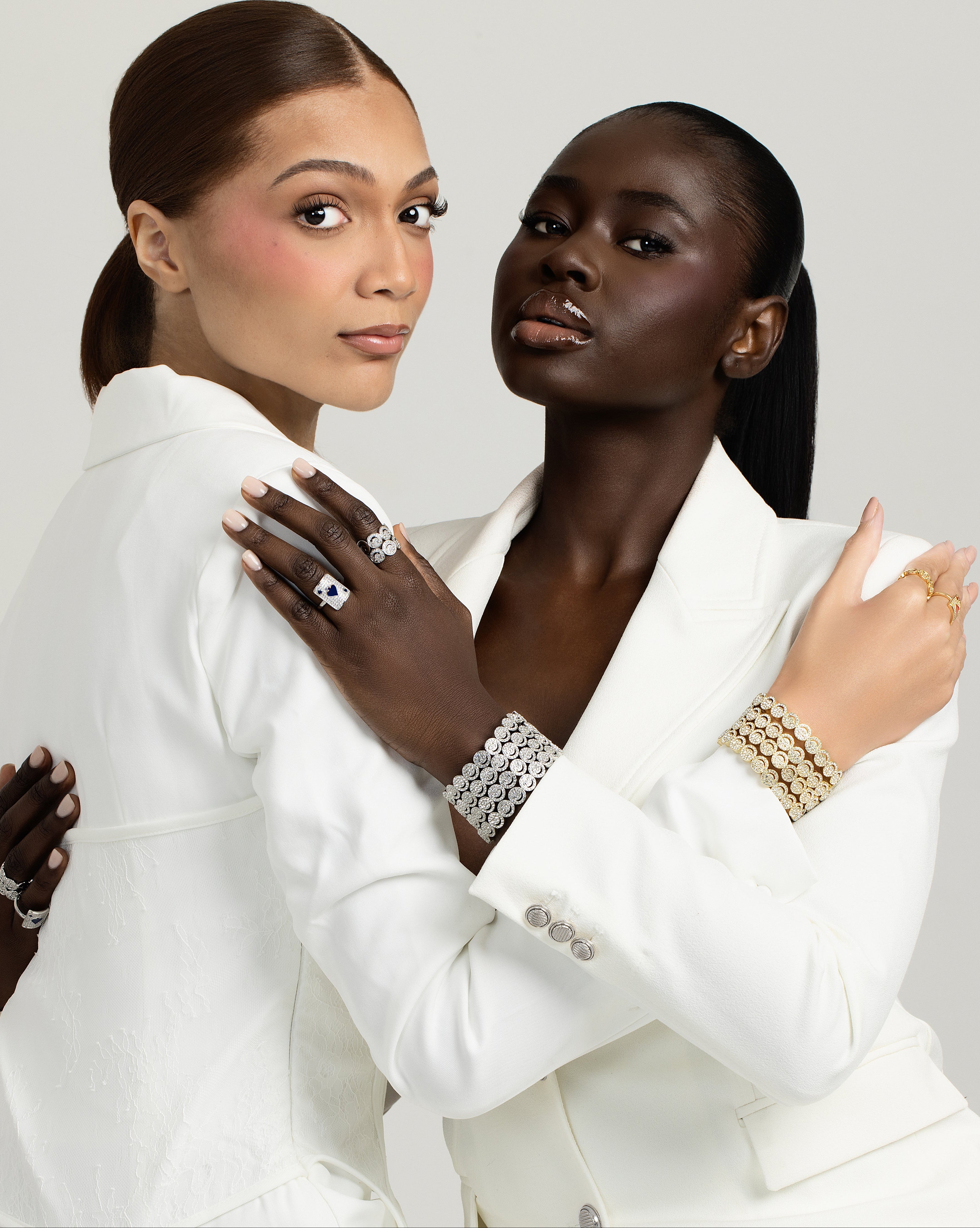 Two women in white outfits with Nymher jewelry on a light gray background
